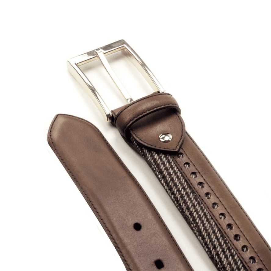 Detail van een bruine tweed riem met cognac brogues baan. Zilverkleurige gesp.