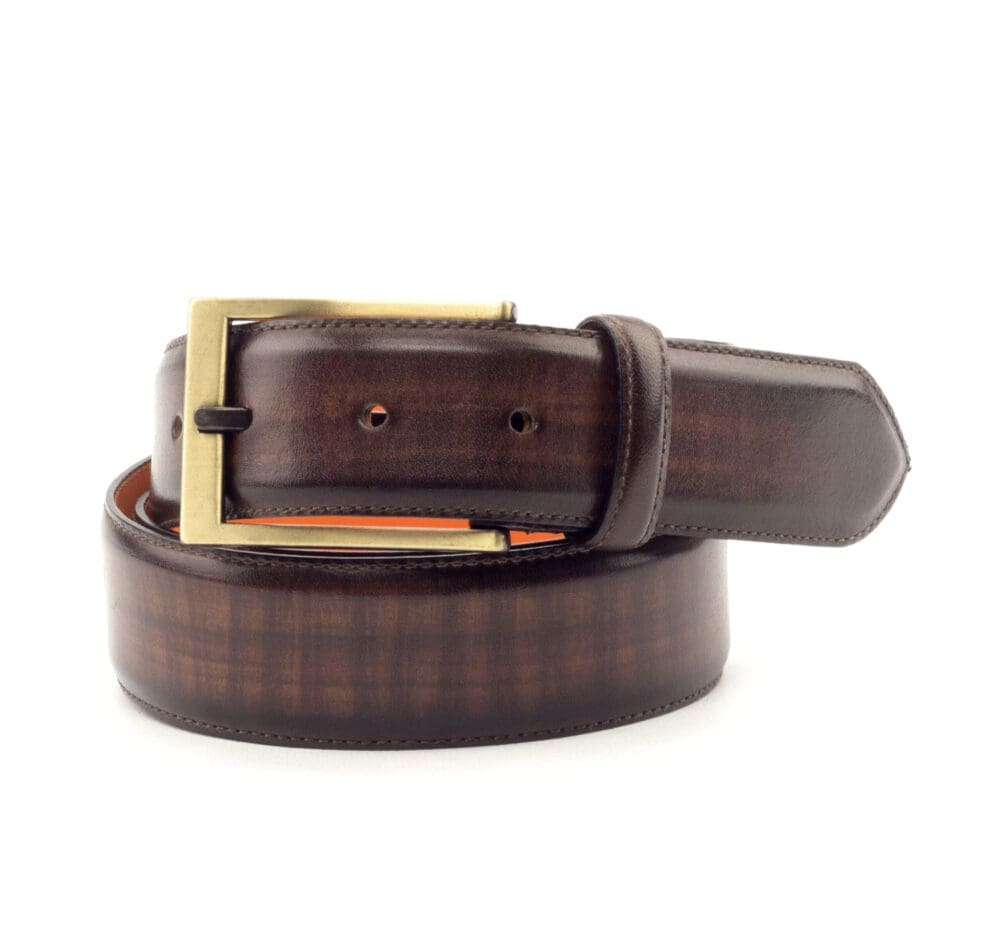 Riem met goudkleurige rechthoekige gesp. Uitgevoerd in bruin patina en met oranje leer gevoerd.