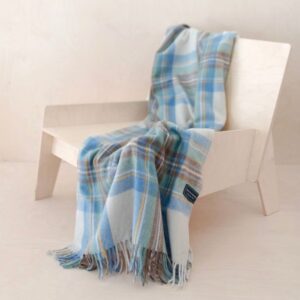 Stewart tartan deken of omslagdoek in lichtblauw liggend over een stoel.