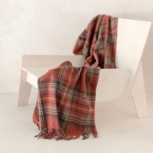Stewart tartan omslagdoek of deken in warm oranje kleuren liggend over een stoel
