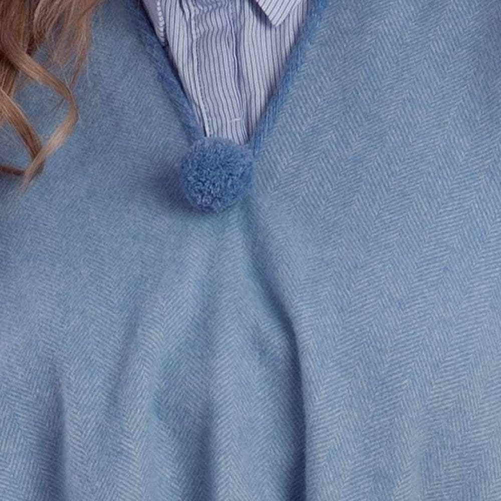 Halslijn van een lichtblauwe poncho met pompom